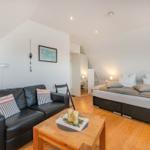 Schlafzimmer mit Sofa, Bett und Holzboden. An der Wand hängt ein Bild.