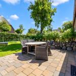 Terrace with table and chairs, garden area with lounge chair and greenery.