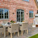 Terrasse mit Esstisch, Stühlen und Sonnenschutz vor Backsteinhaus