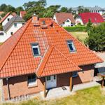 Ein Haus mit rotem Ziegeldach, weißer Tür und Garten.