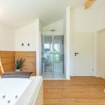 Dusche mit Glaswand, Whirlpool und Holzfußboden