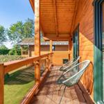 Holzveranda mit zwei grünen Sesseln und Blick auf Garten und Nachbarhäuser.