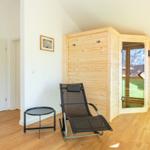 Sauna mit Holzwand und Sitzgelegenheit im Raum mit Holzboden.