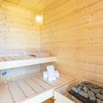 Sauna mit Holzwand, Sitzbänken und Steinen. Handtuch liegt auf der Bank.