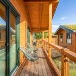 Holzveranda mit Stuhl und Tisch, Blick auf grünen Dachbereich und Nachbarhaus.