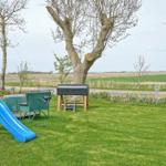 Backyard with playground, grill, and trees. Lawn and fields in the background.