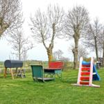 Garden with playground, grill, and picnic table under trees.