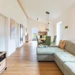 Wohnzimmer mit Sofa, Fernseher und Blick in die Küche