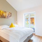 Schlafzimmer mit Bett, Nachttisch und Fenster zur Terrasse.