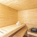 Sauna mit Holzwand, Bank und Heizung. Handtuch liegt auf der Bank.