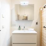 Badezimmer mit Waschbecken, Spiegel und Holzwand