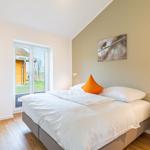 Schlafzimmer mit Bett, Nachttisch und Fenster zur Außenterrasse.