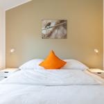 Schlafzimmer mit Bett, zwei Nachttischen und Wandbild eines Vogels.