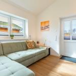 Wohnzimmer mit Sofa, Fenster und Tür. Holzboden und Wandbild.