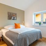 Schlafzimmer mit Bett, Nachttisch und Fenster. Wandbild eines Fuchses.