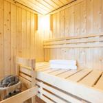 Sauna mit Holzwand und -bänken, Steinkessel und gefalteten Handtüchern.