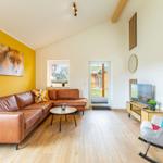 Wohnzimmer mit braunem Sofa, gelber Wand und Fernseher.