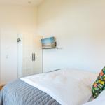 Schlafzimmer mit Bett, Kleiderschrank und Wand-TV.