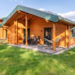 Holzhaus mit Terrasse, Tisch, Stühlen und Hängematten im Garten.