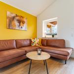 Ein Wohnzimmer mit braunem Sofa, gelber Wand und Wandbild eines Fuchses.