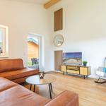 Wohnzimmer mit braunem Sofa, Schaukelstuhl und Fernseher auf Holzregal.
