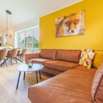 Ein Wohnzimmer mit braunem Sofa, gelber Wand und Wandbild eines Fuchses.