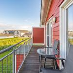 Terrace with table and chairs, view of houses and green areas.