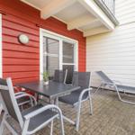 Terrace with table, chairs, and lounge. Red and white wooden structure.