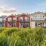 Row of colorful vacation homes with balconies and grass in the foreground.