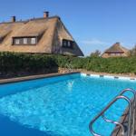 Pool mit Holzdeckung und Stufen. Im Hintergrund Thatched House mit grüner Hecke.
