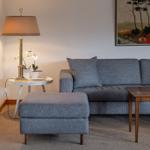 Ein Wohnzimmer mit grauem Sofa, Beistelltisch und Stehlampe.