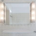 Badezimmer mit Spiegel, zwei Lampen und einer Badewanne