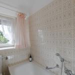 Badezimmer mit Badewanne, Fenster und floralen Fliesen