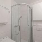Badezimmer mit Dusche, Handtuchhalter und Waschmaschine.