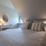 Schlafzimmer mit Dachschrägen, Bett, Nachttisch und Schminktisch mit Spiegel.