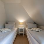 Zwei Betten mit Kissen und einer Lampe zwischen ihnen unter einem Dach