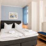 Bedroom with double bed, blue curtains, and wall pictures.