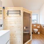 Bad mit Sauna, Waschbecken und Toilette. Holzwände und Fensterblick.