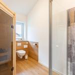 Bad mit Dusche, Toilette und Sauna. Holzfußboden und Fenster mit Blick.