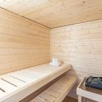 Sauna mit Holzwand, Sitzbank und Heizung mit Steinen.
