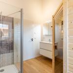Bad mit Dusche, Waschbecken und Holzsauna.
