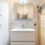 Badezimmer mit Waschbecken, Spiegel und Holzwand