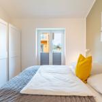 Schlafzimmer mit Bett, Schrank und Blick auf Außenbereich.