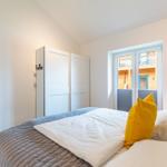 Schlafzimmer mit Bett, Schrank und Fenster zur Außenseite.