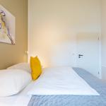 Schlafzimmer mit Bett, Kissen und Wandbild eines Vogels.