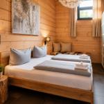Schlafzimmer mit Holzwand, Bett, Kleiderschrank und Wandbild.