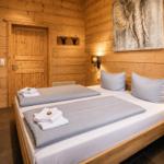 Schlafzimmer mit Holzwand, Bett, Nachttisch und Wandbild.