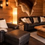 Wohnzimmer mit braunem Ledersofa, Holzwand und Felldekoration.