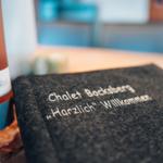 Willkommen-Notizbuch und Weinflasche auf Tisch im Chalet Bocksberg.