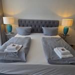 Schlafzimmer mit Doppelbett, zwei Nachttischen, Spiegel und Stühlen.